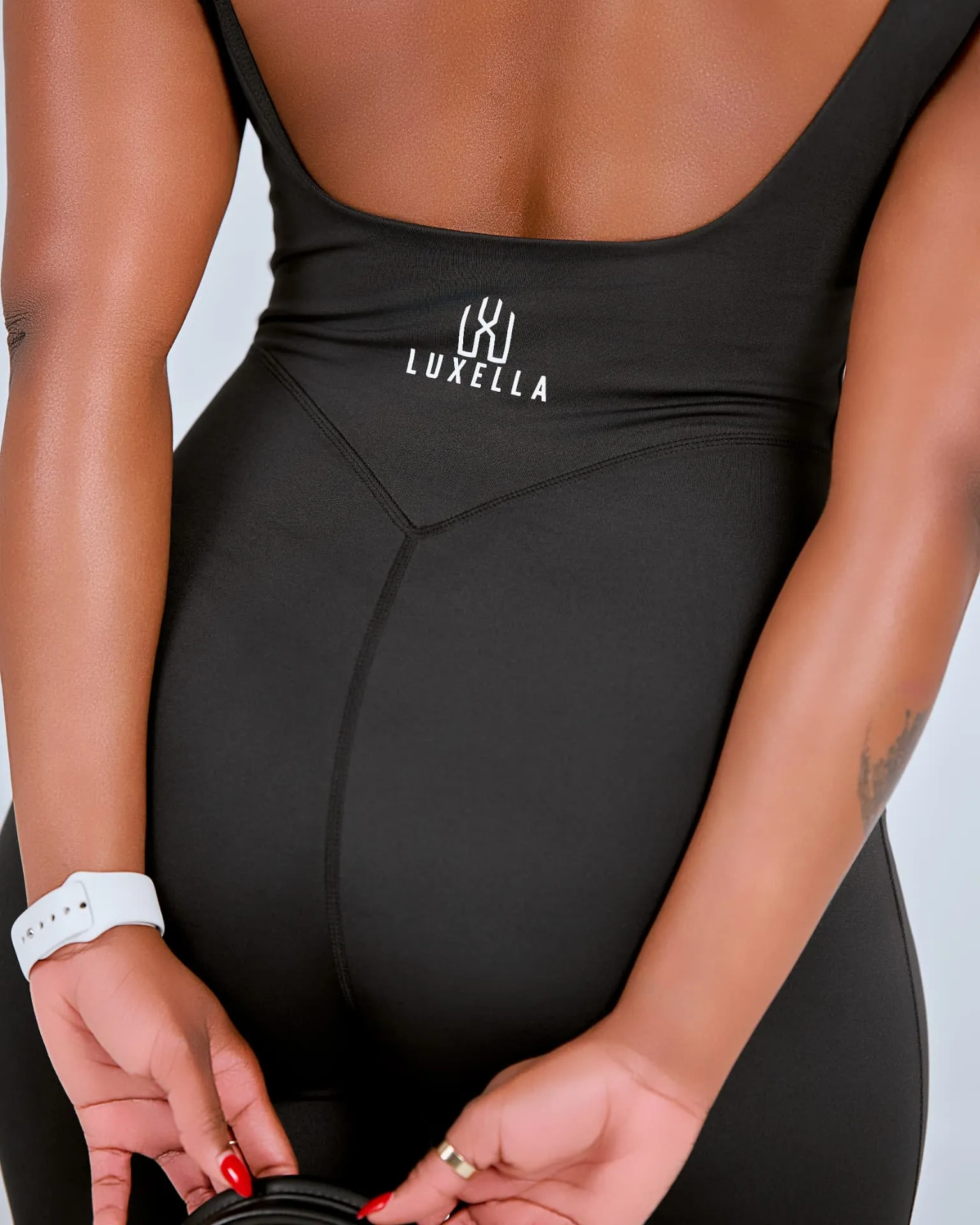Luxella logo detail on a black performance bodysuit
