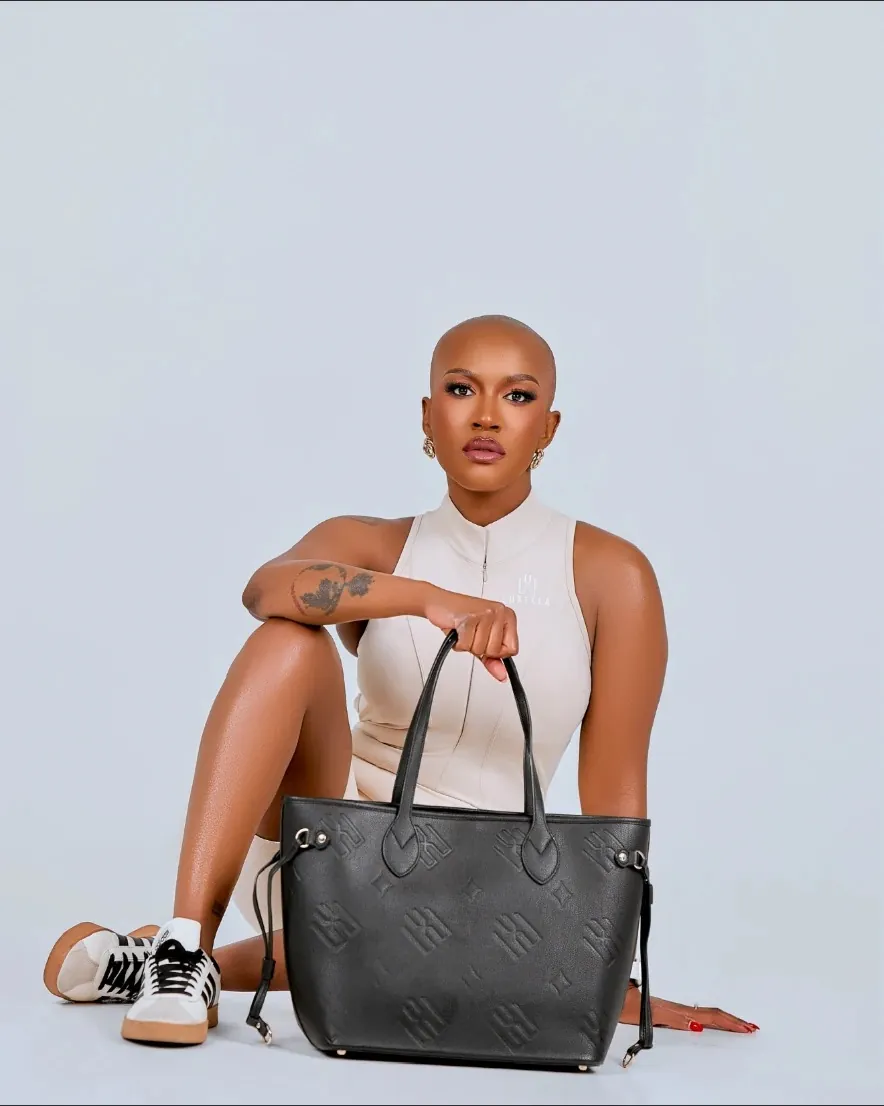 Seated studio portrait in bone performance suit with the Monogram Neverfull